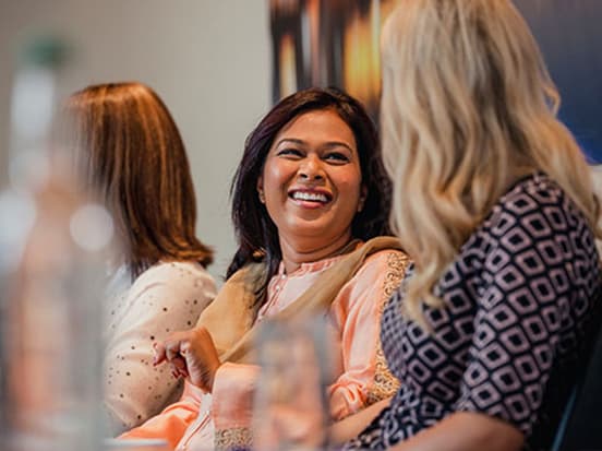 Colleagues sat at a table and smiling at each other
