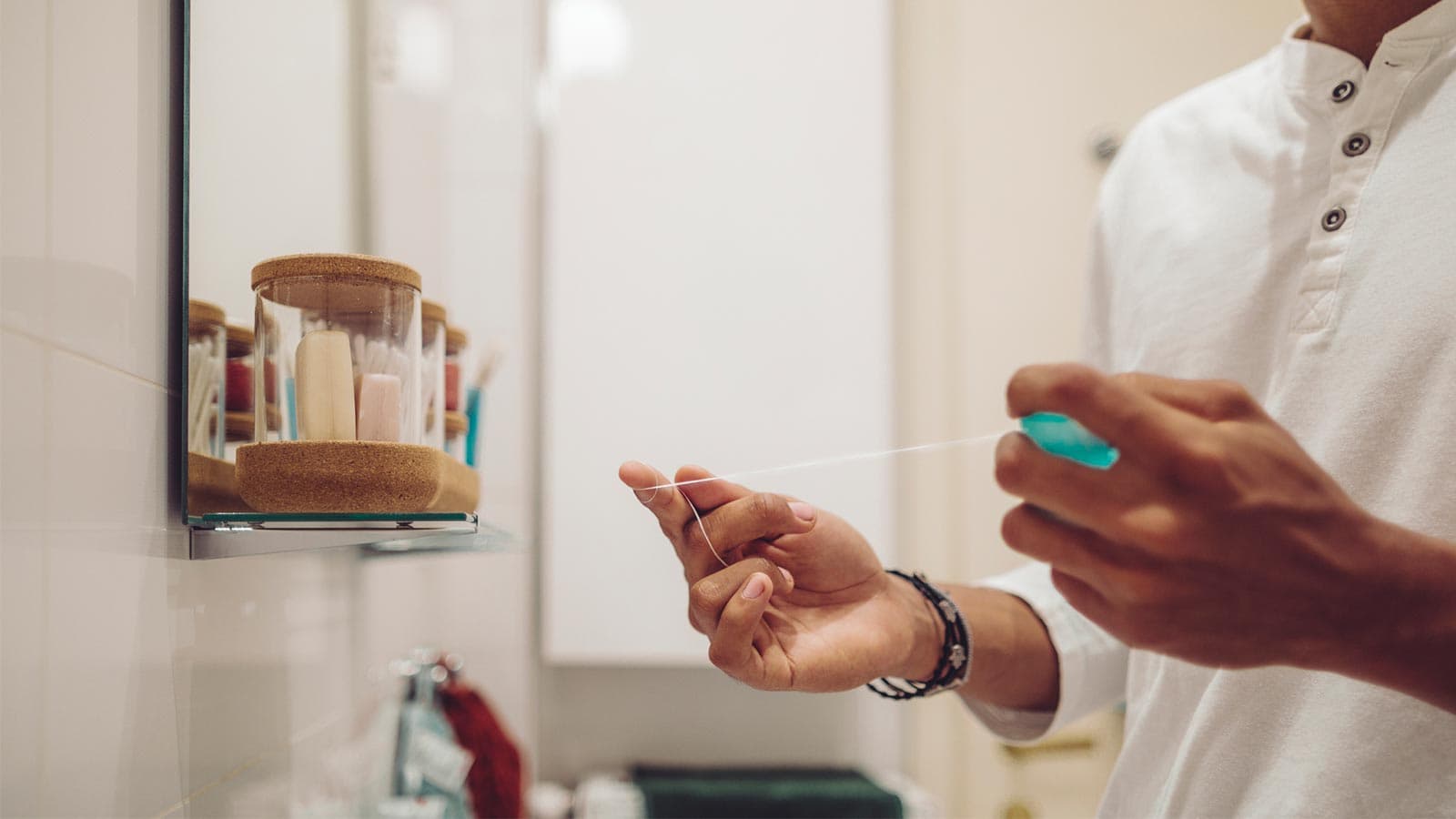 Man with dental floss in his bathroom