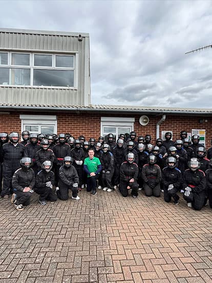 Group of Denplan dentists dressed in helmets and overalls for go karting