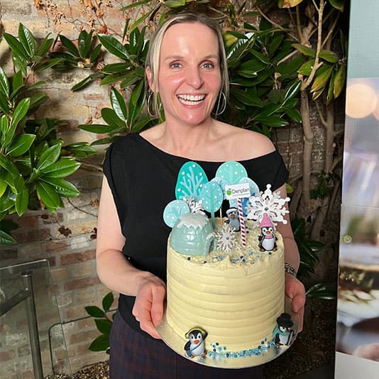 A woman smiles while holding a cake