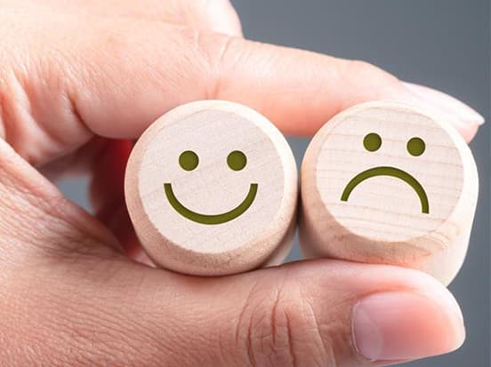 Happy and sad faces held between fingers