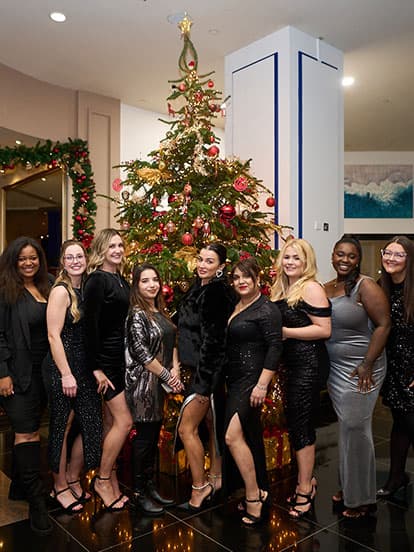 Dental team wearing black tie dress, standing in front of a Christmas tree